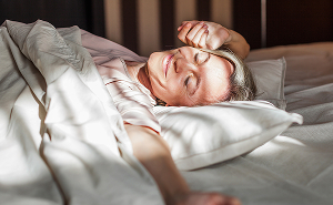 Woman resting peacefully in bed, representing better sleep and energy after menopause treatment.
