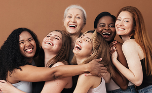 Group of diverse women hugging and laughing together, representing community and trust in women’s hormone treatment.