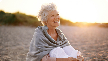 Older woman sitting outdoors in sunlight, reflecting postmenopause health challenges like weight gain, low energy, and hormone therapy solutions.