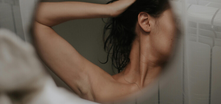 Woman adjusting her hair in front of a mirror, representing how Free T3 thyroid testing helps assess energy, metabolism, and overall hormonal balance.