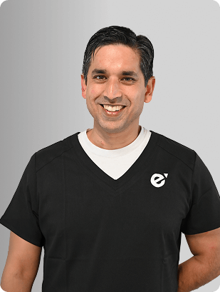 Andrew Abraham, MD, Physician at Fem Excel, smiling in black medical uniform.