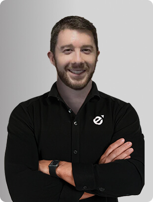 Jonathan Figg, MD, Physician at Fem Excel, smiling in black shirt with arms crossed.