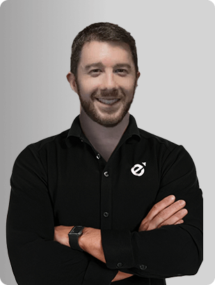 Jonathan Figg, MD, Physician at Fem Excel, smiling in black shirt with arms crossed.