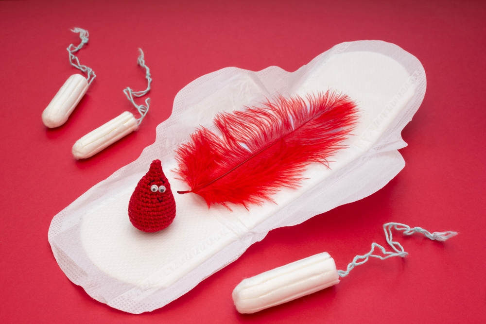 Modern medical concept photo: artistic red smile-shaped crochet, blood drop, pad and tampons. Empowering women's health, breaking taboos. Sanitary woman hygiene is not a taboo