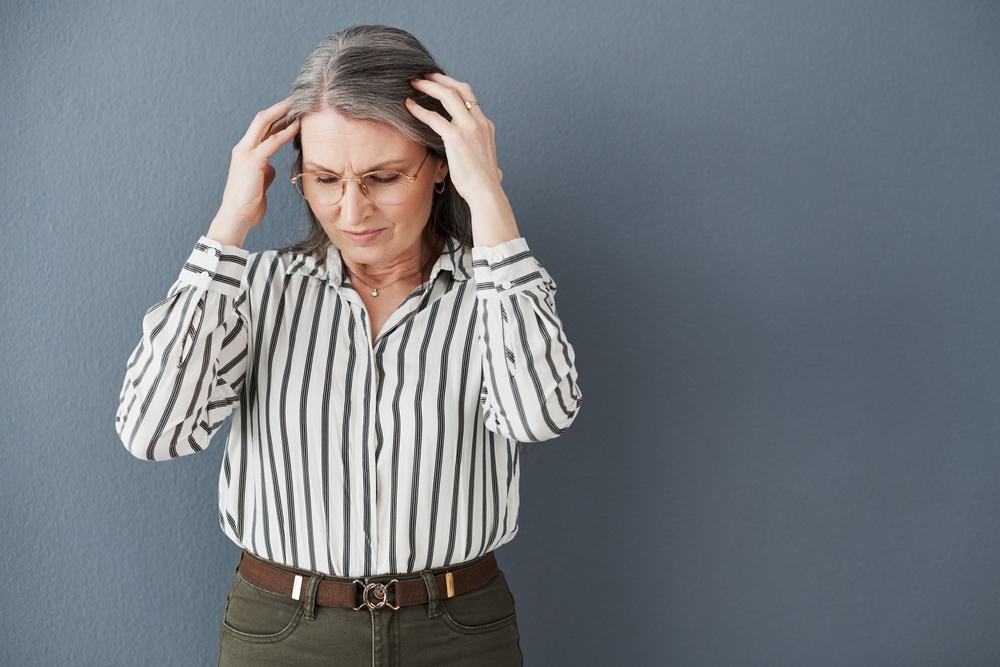 Upset senior woman with hands on head from brain fog Upset senior woman with hands on head from brain fog