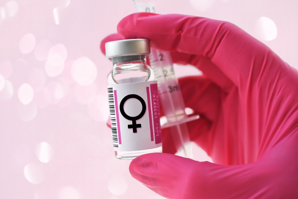 Pink gloved hand holding a vial with female symbol estrogen hormone concept