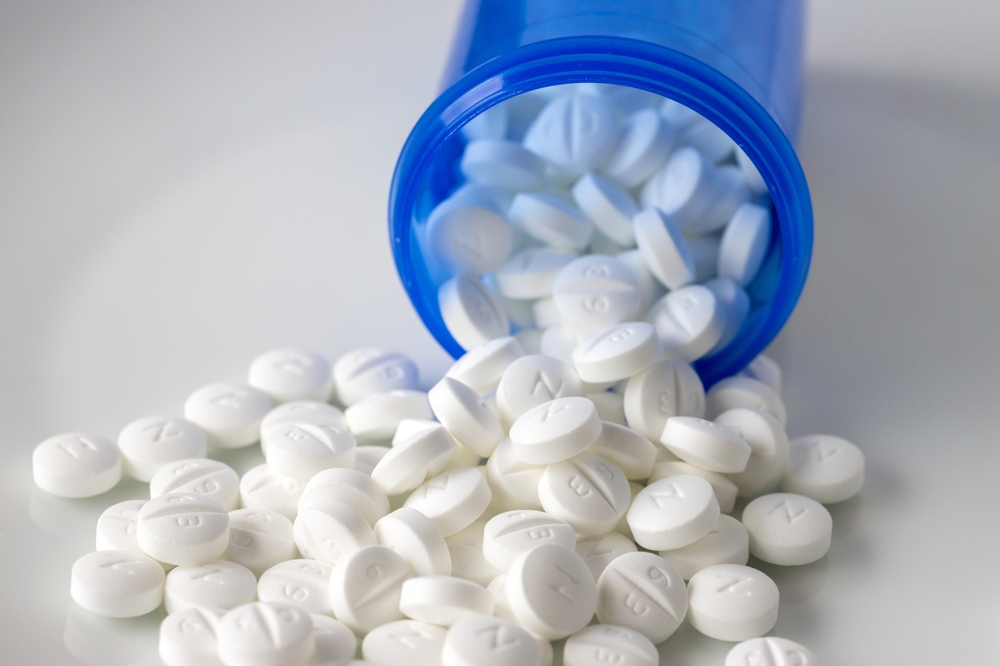 white Metformin pills spilling out of blue bottle