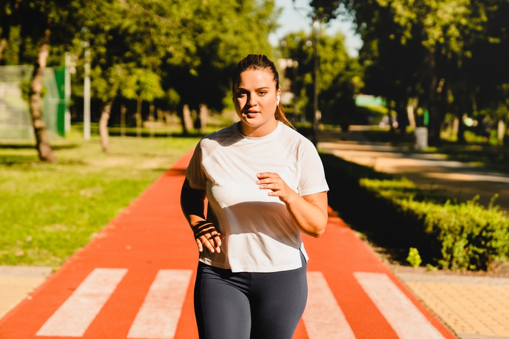 Body positive plus size plump woman jogging in park