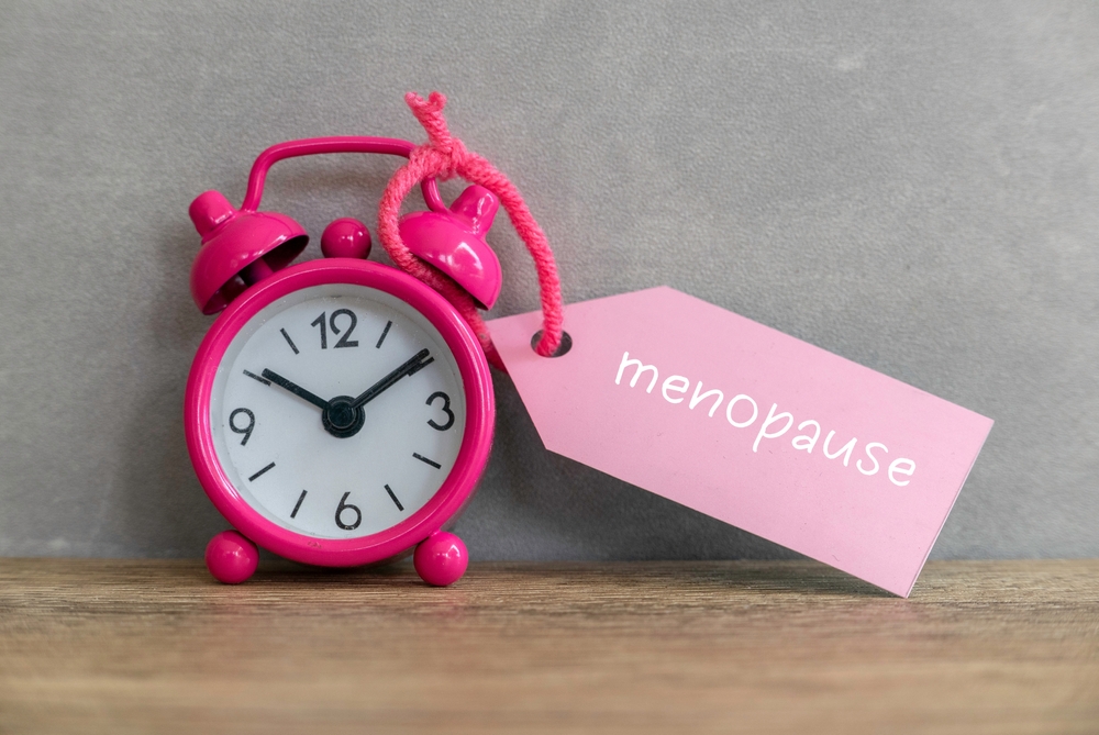 Pink Alarm Clock next to the word menopause written on pink paper strip