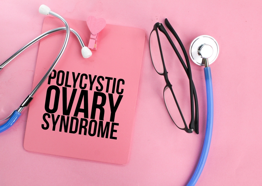 stethoscope glasses and a pink clipboard with the words Polycystic Ovary Syndrome in black text