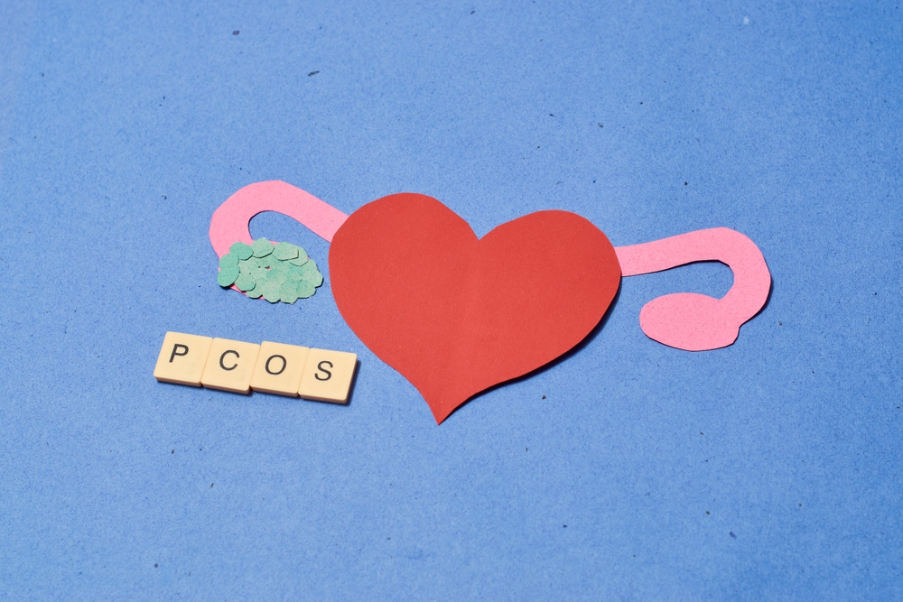 Concept of polycystic ovary syndrome shown with paper cut out of heart and female reproductive system