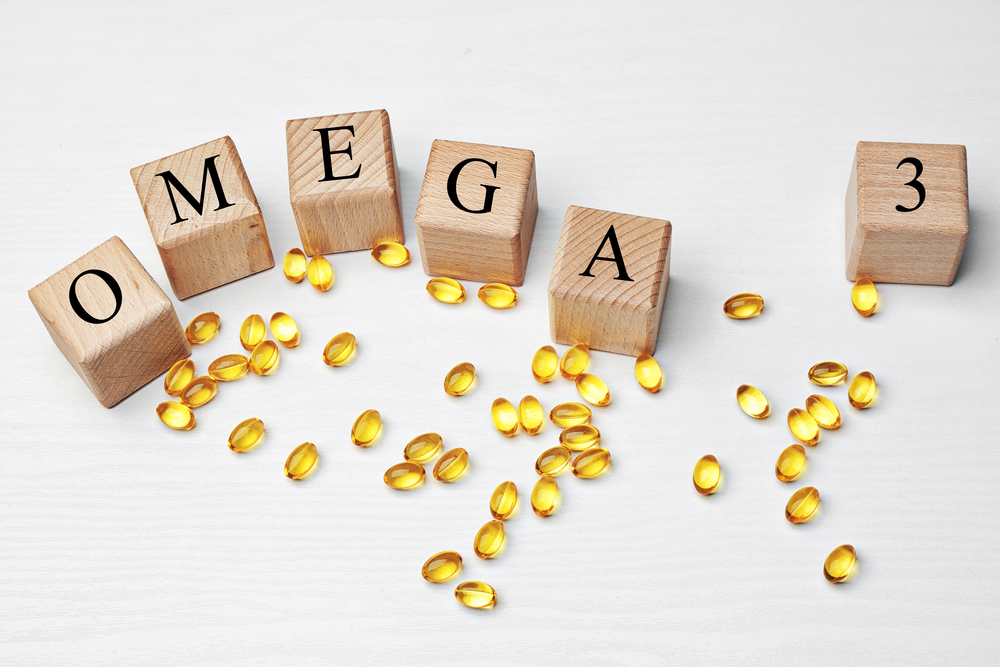 Fish oil pills and wooden cubes with inscription OMEGA 3 on light background