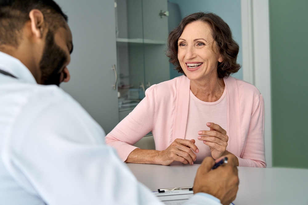 Happy older mature female patient talking to male doctor