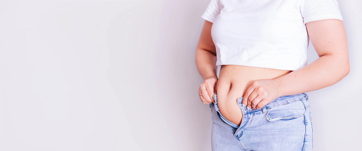 cortisol and weight gain hero. Woman doing jeans up.