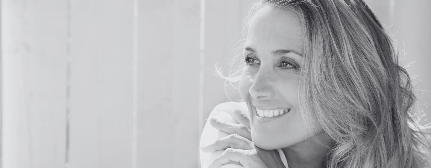 Smiling middle-aged woman looking out a window in natural light